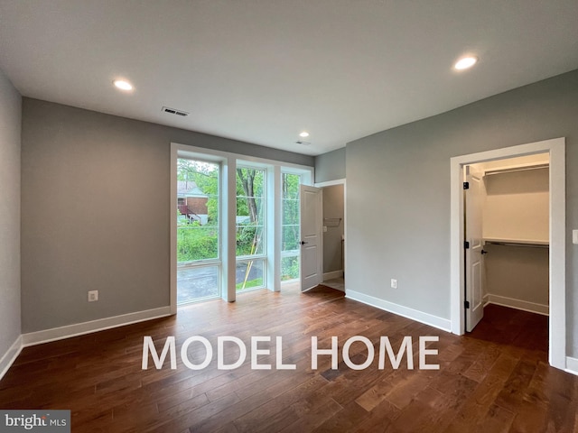 unfurnished bedroom with a closet, dark hardwood / wood-style floors, and a spacious closet