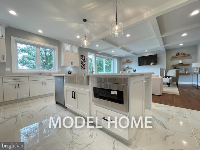 kitchen featuring appliances with stainless steel finishes, coffered ceiling, white cabinetry, decorative light fixtures, and a kitchen island