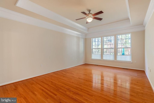 unfurnished room featuring crown molding, light hardwood / wood-style floors, ceiling fan, and a raised ceiling