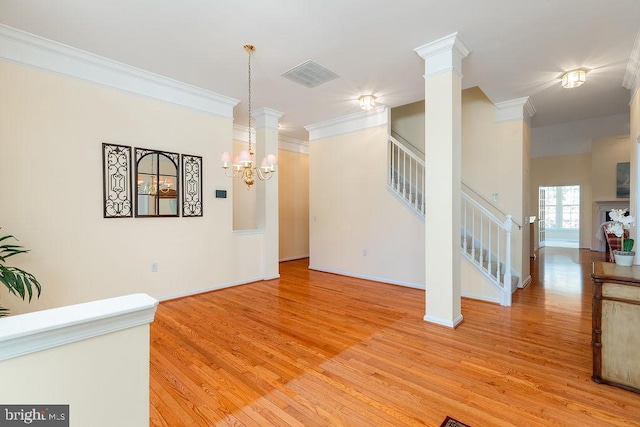 interior space featuring light hardwood / wood-style floors, ornate columns, an inviting chandelier, and ornamental molding