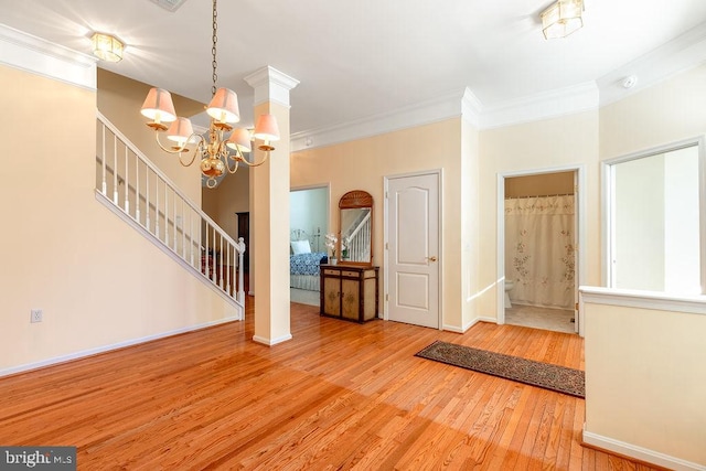 foyer entrance featuring an inviting chandelier, hardwood / wood-style flooring, and crown molding