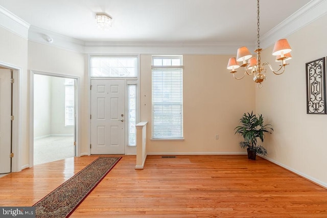 foyer with ornamental molding, a notable chandelier, and light hardwood / wood-style floors