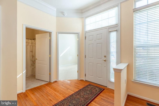 foyer featuring light wood-type flooring and crown molding