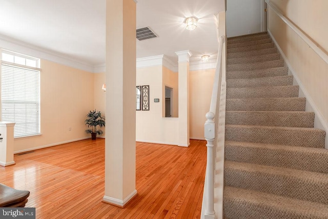 stairs featuring ornamental molding and hardwood / wood-style flooring