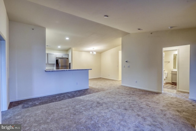 unfurnished living room with carpet floors and an inviting chandelier