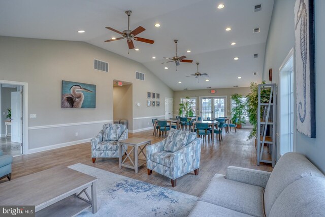 living room with light wood-type flooring, ceiling fan, and high vaulted ceiling