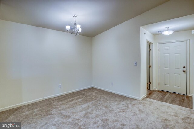 empty room with light carpet and a notable chandelier