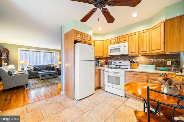 kitchen featuring light wood-type flooring, white appliances, backsplash, and ceiling fan