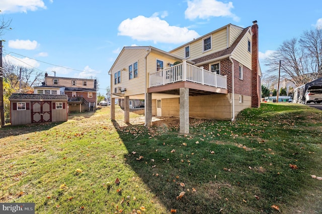 rear view of house with a yard, a deck, and a storage shed