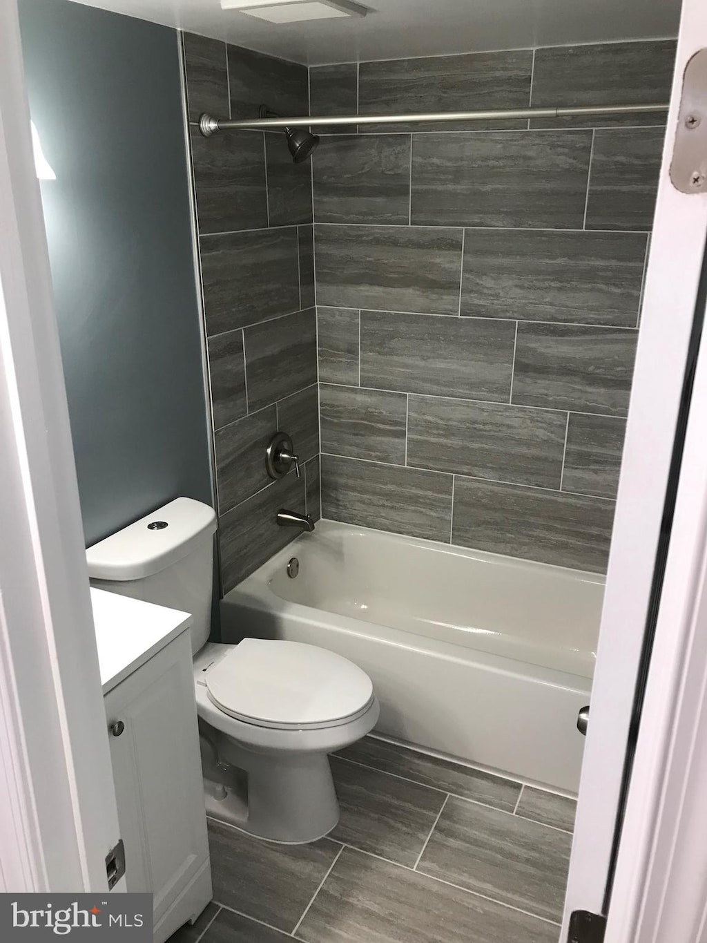 full bathroom featuring vanity, tiled shower / bath combo, and toilet