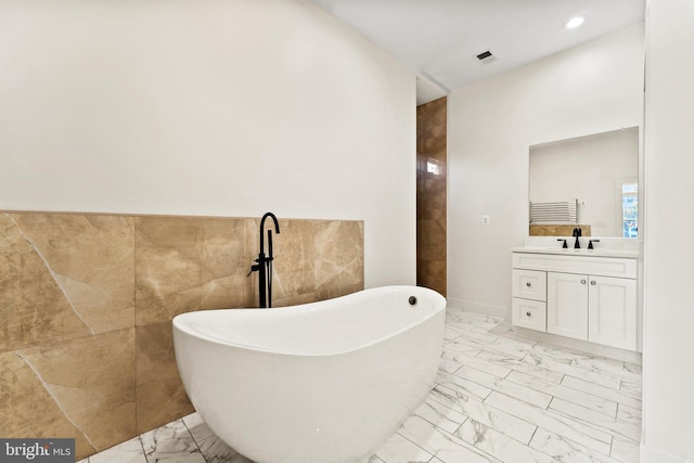 bathroom featuring vanity, a bathtub, and tile walls