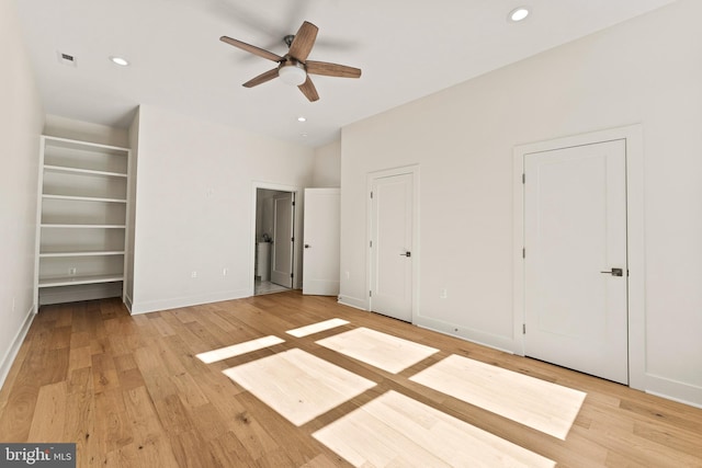 unfurnished bedroom with ceiling fan, two closets, and light wood-type flooring