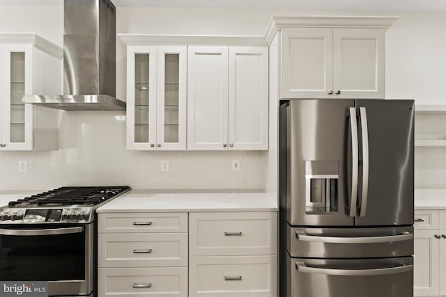 kitchen with tasteful backsplash, white cabinets, stainless steel appliances, and wall chimney range hood