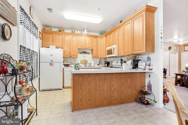 kitchen with white appliances, kitchen peninsula, and light brown cabinetry