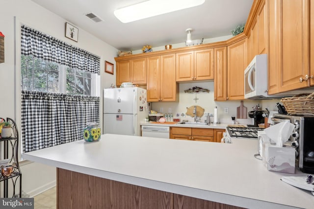 kitchen featuring kitchen peninsula, sink, and white appliances