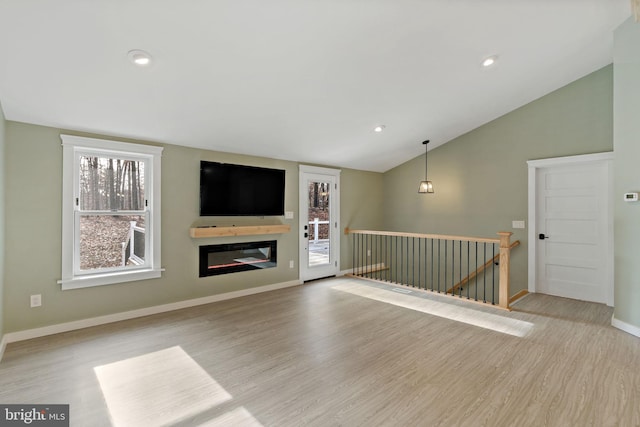 unfurnished living room with a healthy amount of sunlight, lofted ceiling, and light hardwood / wood-style floors