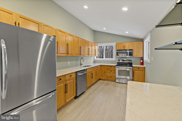 kitchen featuring sink, stainless steel appliances, vaulted ceiling, and light wood-type flooring