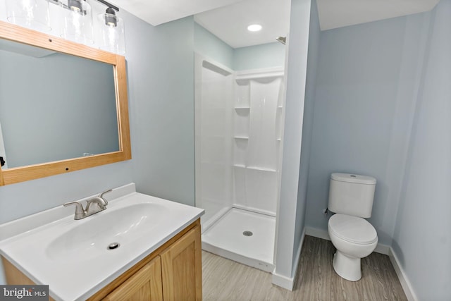 bathroom featuring vanity, toilet, walk in shower, and wood-type flooring