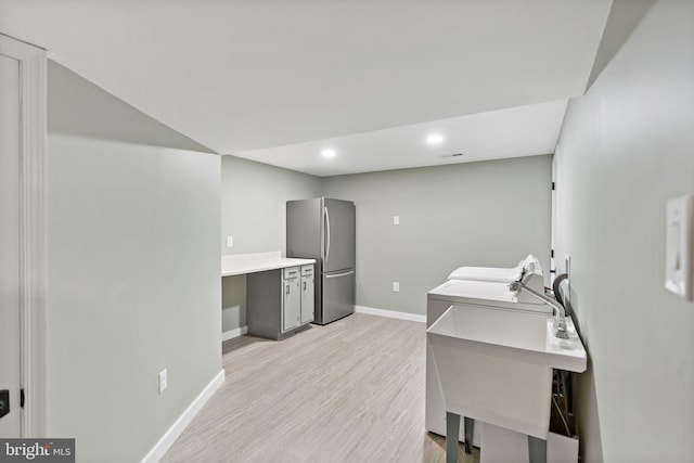 clothes washing area with washer / clothes dryer, sink, and light hardwood / wood-style floors