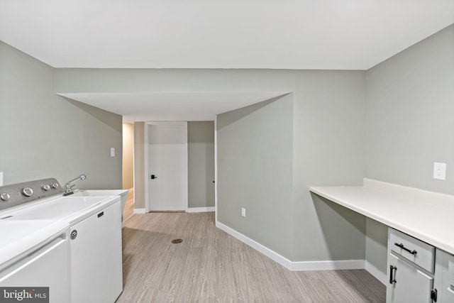 clothes washing area featuring washing machine and dryer, cabinets, and light wood-type flooring