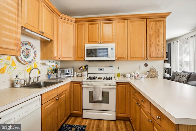 kitchen with kitchen peninsula, sink, light hardwood / wood-style floors, and white appliances