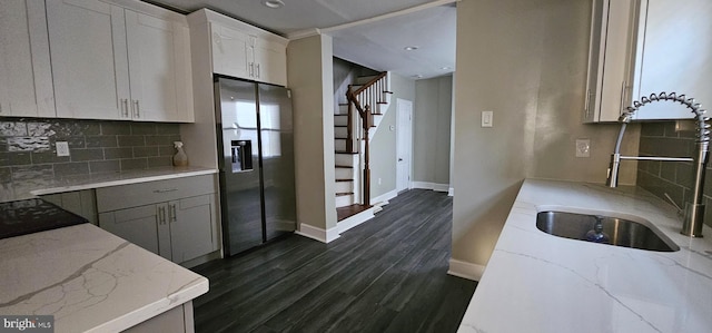 kitchen featuring sink, light stone counters, dark hardwood / wood-style flooring, stainless steel fridge, and white cabinets