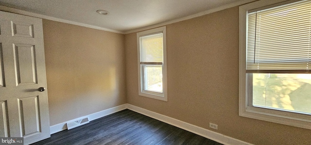 empty room with dark hardwood / wood-style floors, plenty of natural light, and ornamental molding