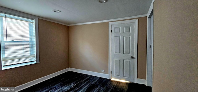 spare room featuring crown molding and dark wood-type flooring