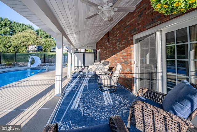 view of swimming pool with a patio, ceiling fan, and a water slide