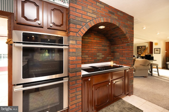 kitchen featuring black electric stovetop, light carpet, and double oven