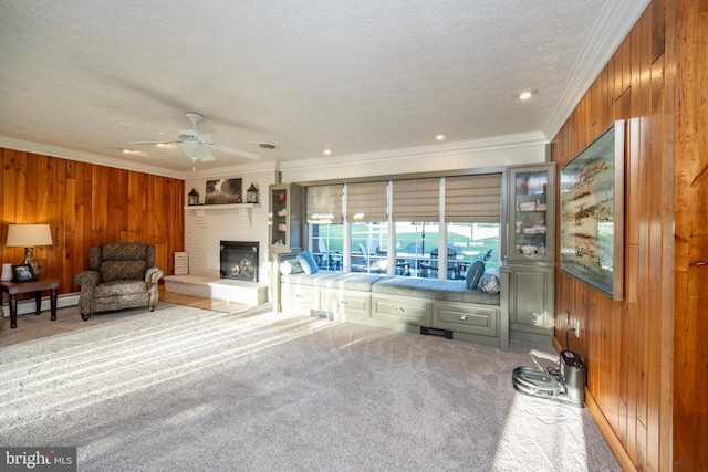 carpeted living room with ornamental molding, a textured ceiling, wooden walls, and ceiling fan