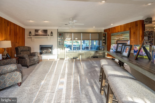 living room with wood walls, ceiling fan, carpet floors, and ornamental molding