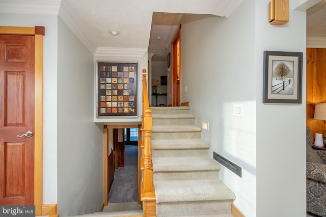 stairs featuring a textured ceiling and crown molding