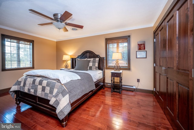 bedroom featuring ornamental molding, a baseboard heating unit, dark hardwood / wood-style floors, and ceiling fan