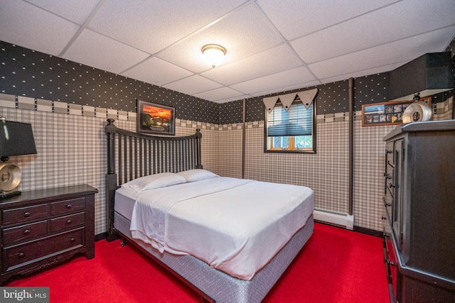 carpeted bedroom featuring baseboard heating and a paneled ceiling