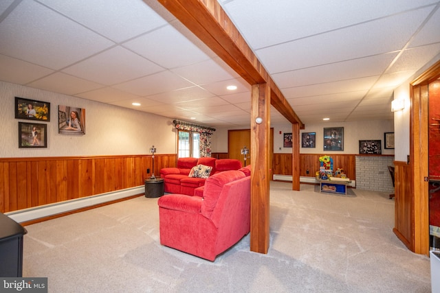 living room featuring wood walls, carpet floors, a baseboard heating unit, and a drop ceiling