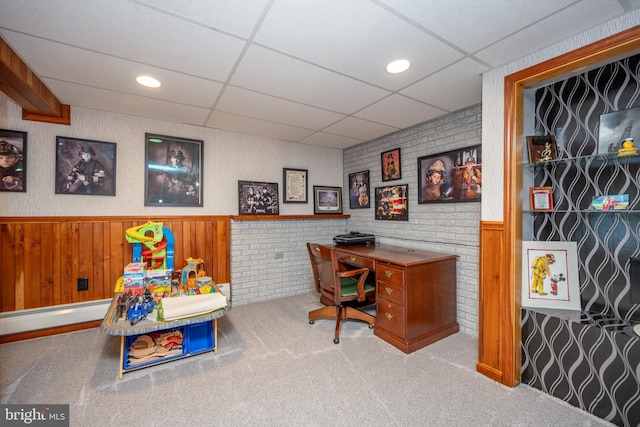 office area featuring a drop ceiling, baseboard heating, wood walls, and carpet floors