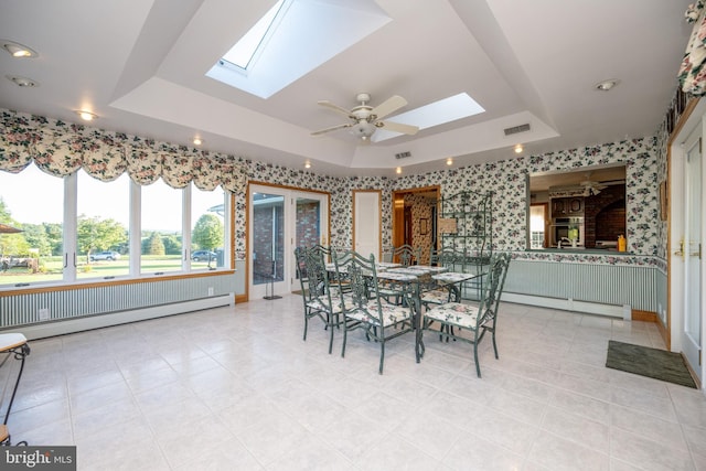 dining room featuring a skylight, baseboard heating, ceiling fan, and a raised ceiling