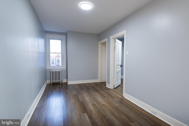 empty room with dark hardwood / wood-style floors and radiator heating unit