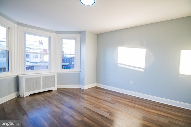 spare room with dark wood-type flooring and radiator