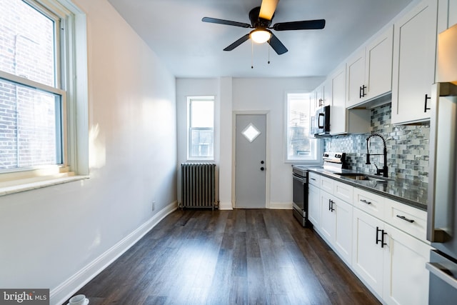 kitchen with white cabinetry, stainless steel appliances, radiator heating unit, and sink