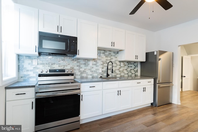 kitchen with tasteful backsplash, stainless steel appliances, sink, light hardwood / wood-style floors, and white cabinets