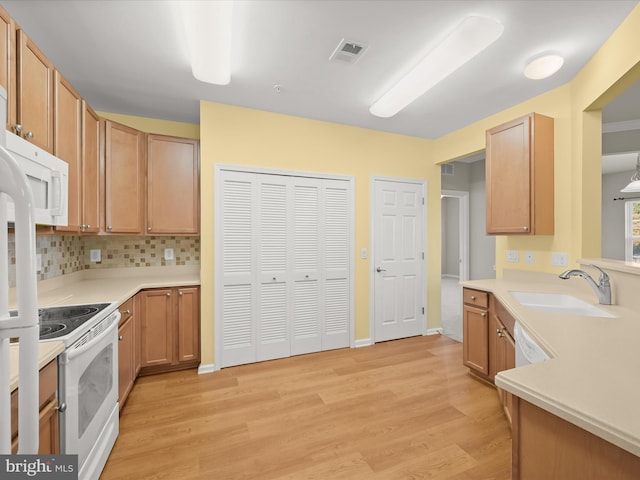 kitchen featuring backsplash, light wood-type flooring, white appliances, and sink