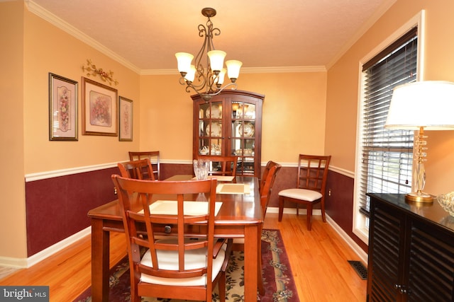 dining area featuring ornamental molding, a notable chandelier, and light hardwood / wood-style floors