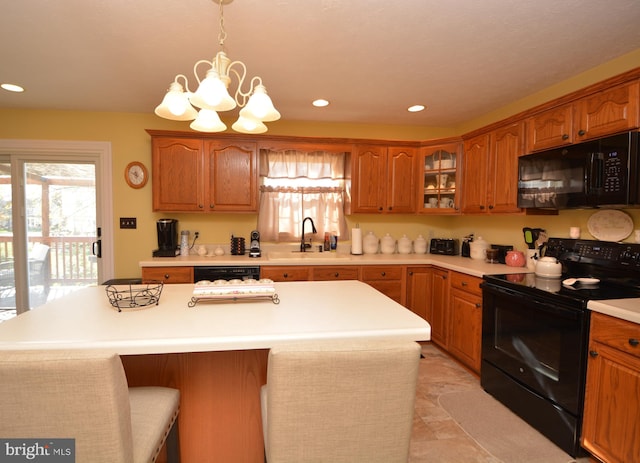 kitchen with a center island, black appliances, sink, a breakfast bar area, and pendant lighting