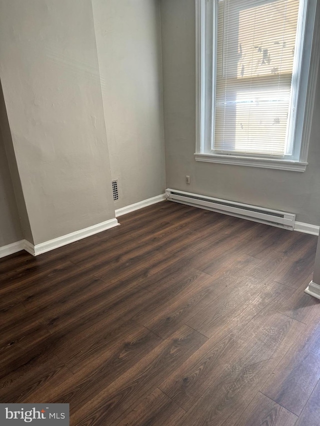 spare room with a baseboard radiator and dark hardwood / wood-style flooring