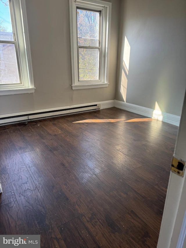 unfurnished room featuring a wealth of natural light, dark hardwood / wood-style floors, and baseboard heating