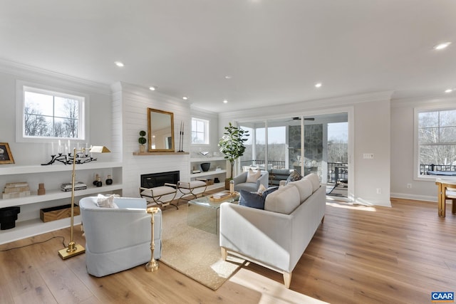 living room featuring a fireplace, plenty of natural light, light wood-type flooring, and ornamental molding