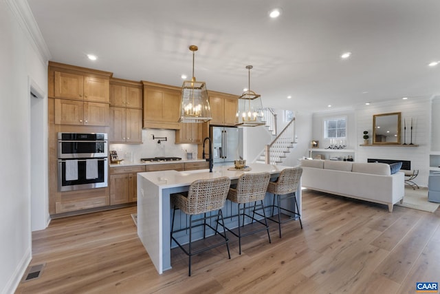 kitchen with stainless steel appliances, a breakfast bar, a large island with sink, and light hardwood / wood-style flooring