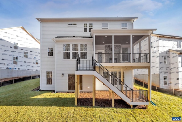 rear view of house featuring a sunroom and a yard